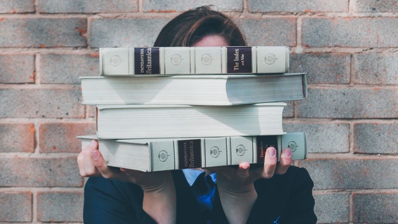 person-holding-stack-of-books-in-front-of-their-face | Canada’s Education System