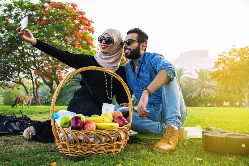 happy Lebanese couple sitting on grass having picnic in park | immigrate to Canada from Lebanon