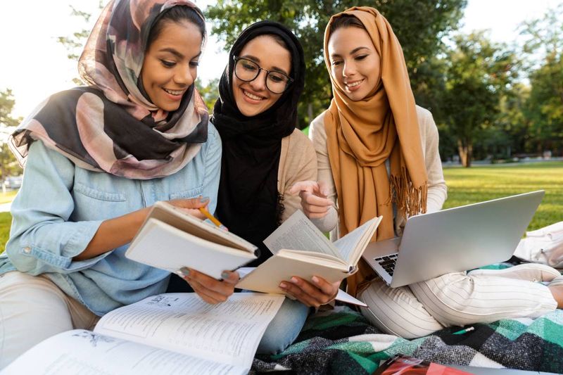 happy female muslim students studying reading books and studying in park | immigrate to Canada from Lebanon